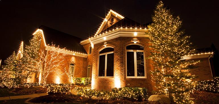 House, trees, and bushes covered in bright Christmas lighting